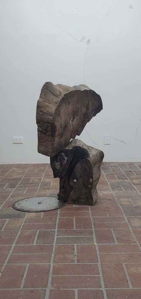 Two stumps stacked next to a metal circular blade lying on the floor.
