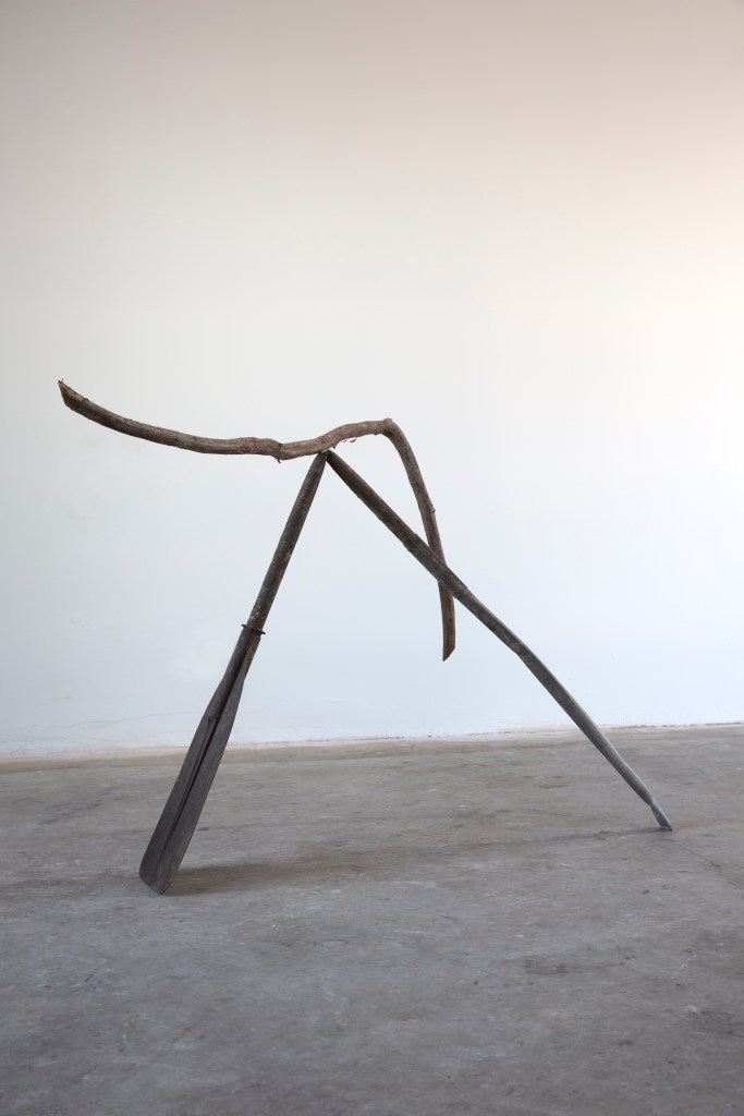 A curbed branch rests on a bent metal oar.