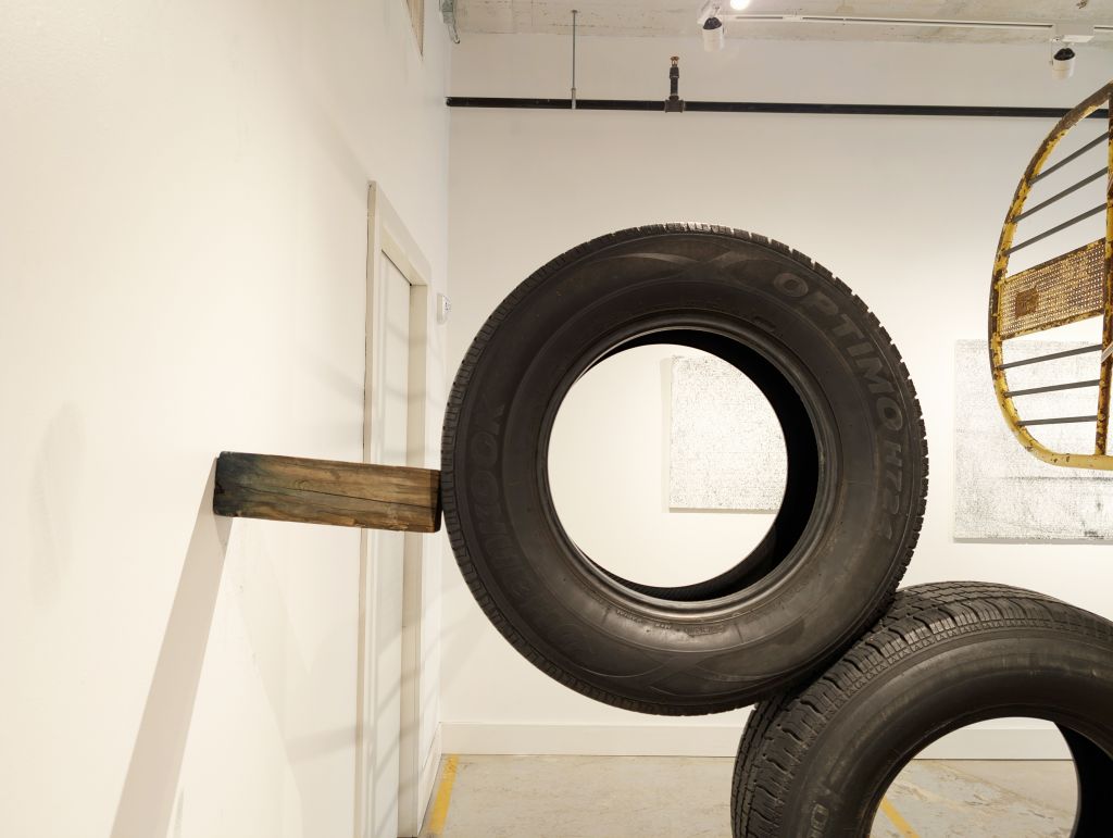 Three tires stacked and wedged between two walls with a wooden block.