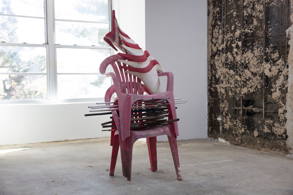 Plastic chairs stacked with object squeezed between them and resting on top.